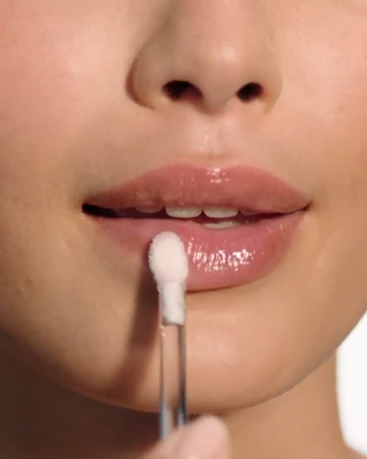 Close up video of applicator swirling through lip balm texture and then female applying lip balm with applicator to her lips.