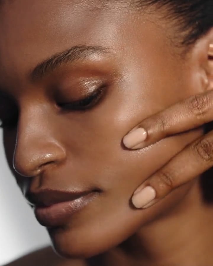 lady applying serum with two fingers across and up her cheekbone.