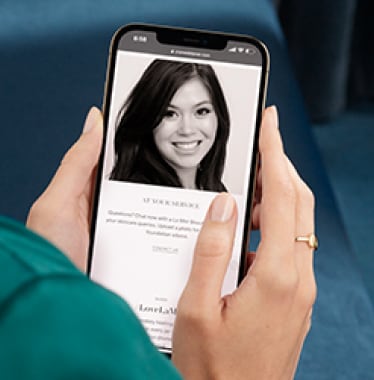 hand holding a mobile phone with lady with dark hair smiling on it